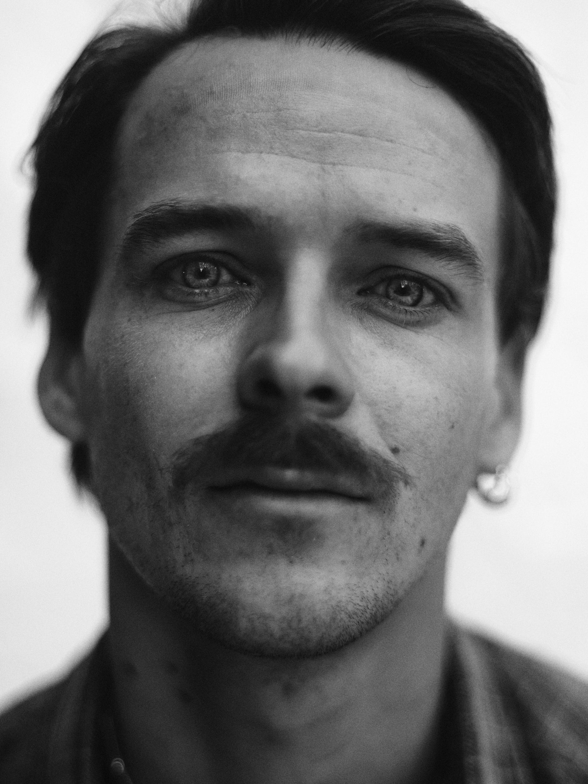  High-quality monochrome headshot of a male model, showcasing expressive eyes and cinematic lighting for commercial and agency representation. Photographed in Amsterdam Studio